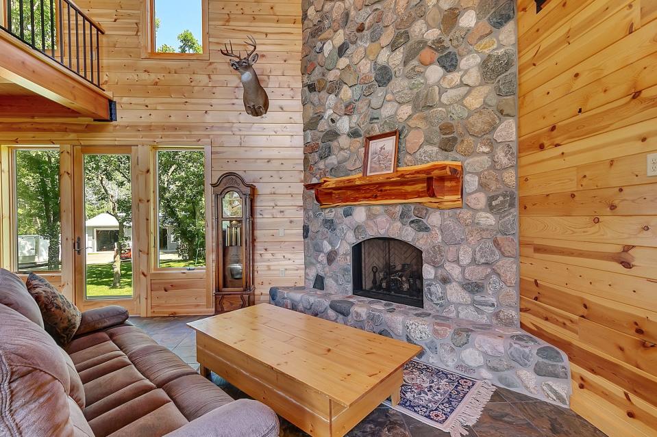 The great room is open and airy with craftsman-style beams traversing the span of the ceiling. The vaulted room touts slate floors with in-floor heat and is open to an overhead loft. A stone fireplace and hearth warm the space while an open bar area provides a space for snacking, relaxing and entertaining.