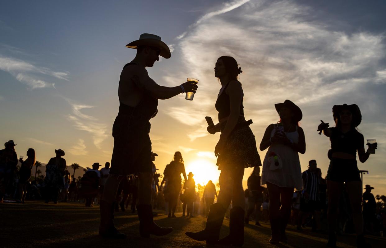 Festivalgoers in 2023 are silhouetted between venues at Stagecoach in Indio, California.