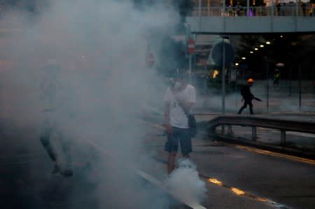 Anti-extradition bill protesters react from tear gas as they face riot police during a march in Hong Kong