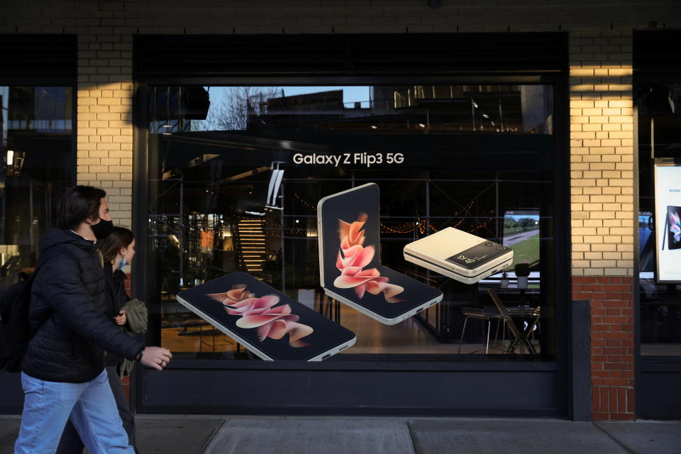 People walk by advertising for the Galaxy Z Flip3 5G cell phones at Samsung 837 in Manhattan, New York City, U.S., November 23, 2021. REUTERS/Andrew Kelly