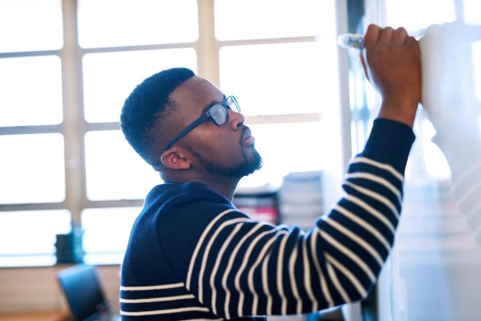 cropped shot of a young man writing on a whiteboard in a classroom