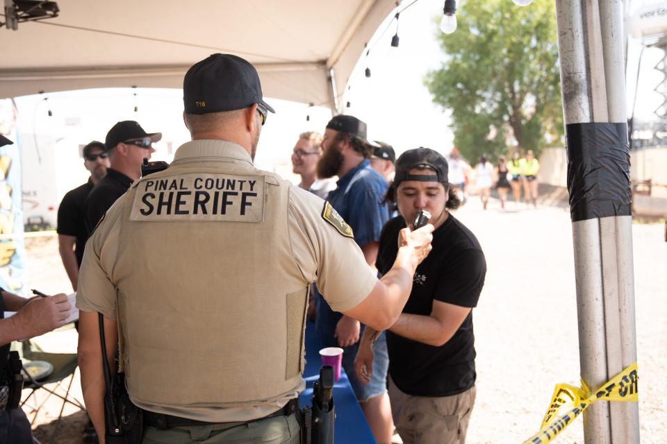 Levi French (right) takes a Breathalyzer test at a booth hosted by the Chandler Police Department and Pinal County Sheriff's Office at the Country Thunder Music Festival campgrounds on April 15, 2023, in Florence.