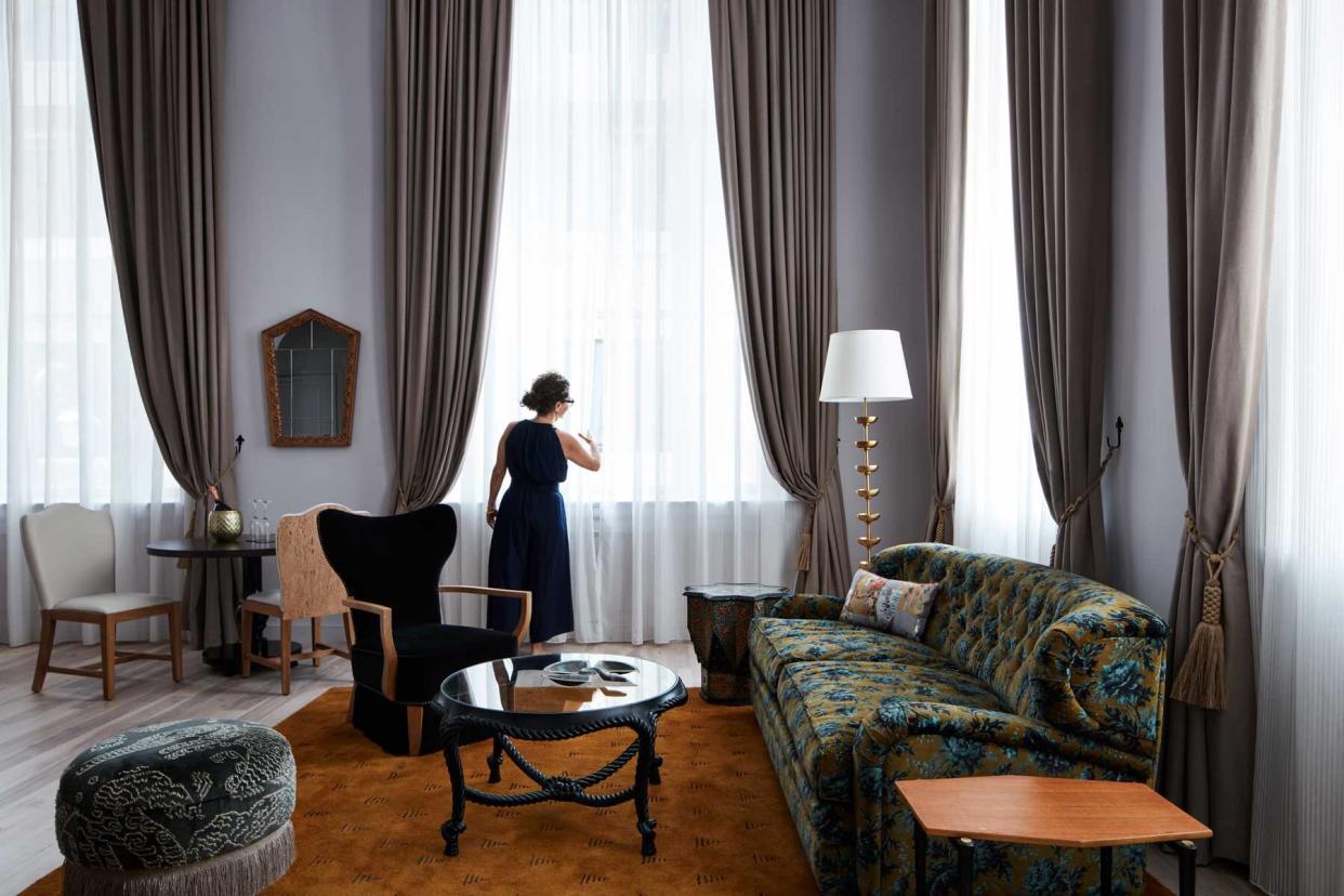 A woman adjusts the curtains in a luxury guest suite at the Maison de la Luz hotel in New Orleans