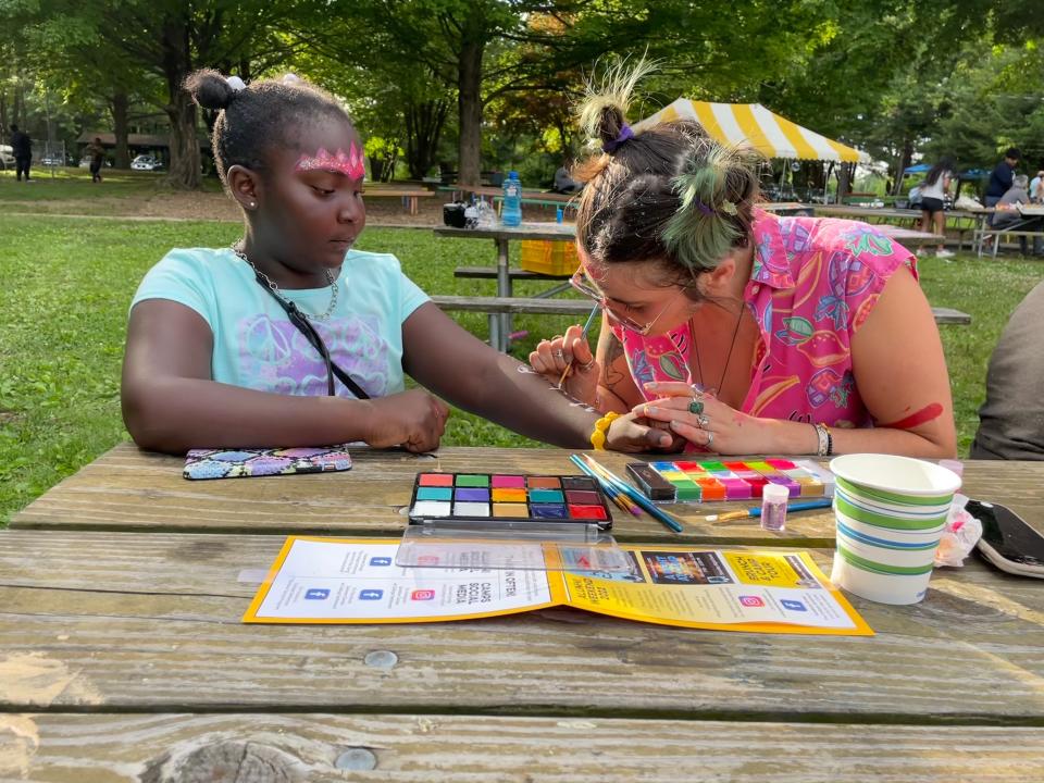 Zoe Colatarci, right, paints Legend Harris' face and arm with decorative paint and glitter at College Settlement Camp's 90th annual June Supper on Thursday, June 9, 2022.