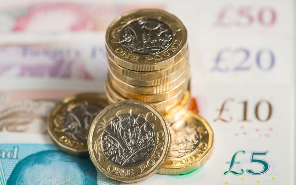 A UK five pound, ten pound, twenty pound and fifty pound notes with one pound coins