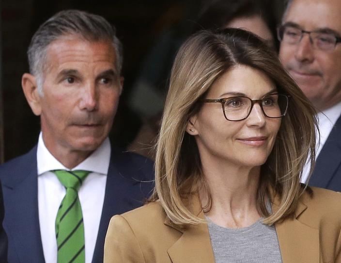 FILE - In this April 3, 2019, file photo, actress Lori Loughlin, front, and her husband, clothing designer Mossimo Giannulli, left, depart federal court in Boston after facing charges in a nationwide college admissions bribery scandal. Giannulli has been released from a California prison, Saturday, April 3, 2021 and is currently at a halfway house outside Los Angeles following his imprisonment for his role in a college admissions bribery scheme, records show. (AP Photo/Steven Senne, File)