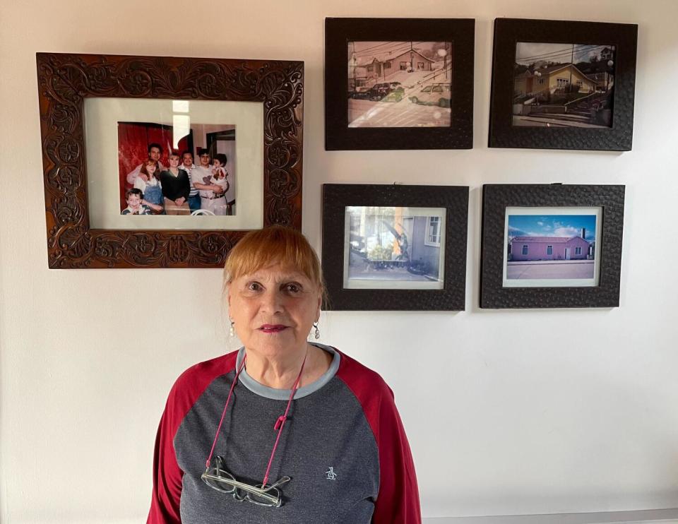 Mar Tita Garea stands in front of framed photographs.