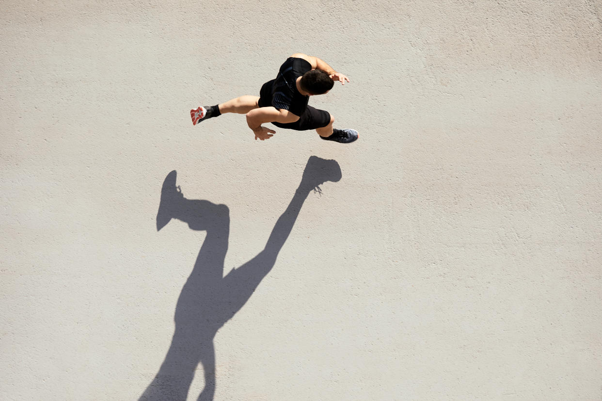 bird's eye view of man running in shorts and sneakers with shadow, best running shorts for men in 2023, 8 best pairs of running shorts for your summer outdoor activities (photo via Getty).