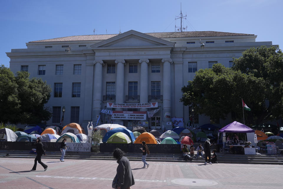 FILE - People walk past tents set up in front of Sproul Hall at UC Berkeley in Berkeley, Calif., Thursday, May 2, 2024. The only thing more American than protests for a cause? Wanting them to pipe down and go away. From the Boston Tea Party to the Civil Rights Movement to last week, U.S. history is filled with the tension between people demonstrating about issues that matter to them and others who want to be left alone. (AP Photo/Jeff Chiu, File)