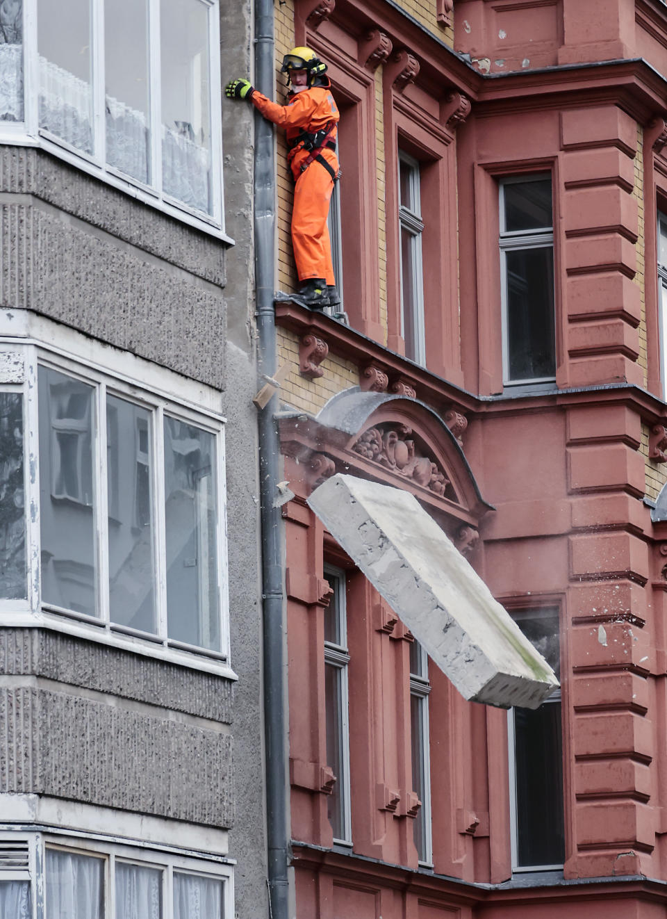 A workman loosens part of a wall damaged in a storm to crash onto the pavement below, in Berlin, Germany, Thursday, Feb. 17, 2022. Meteorologists warned Thursday that northern Europe could be battered by a series of storms over the coming days after strong winds swept across the region overnight. (AP Photo/Hannibal Hanschke)