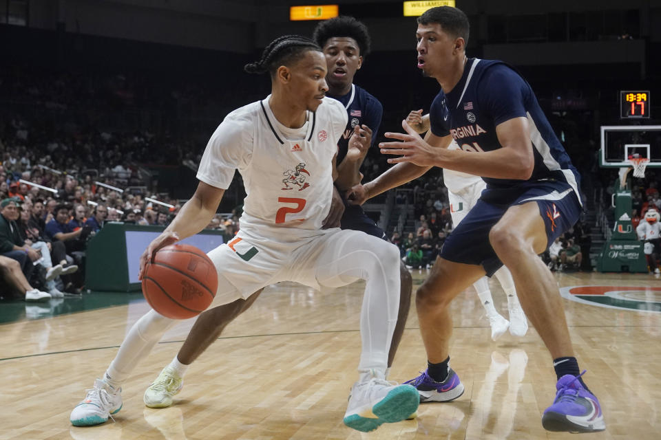 Virginia guard Reece Beekman, center and forward Kadin Shedrick (21) defends Miami guard Isaiah Wong (2) during the first half of an NCAA college basketball game, Tuesday, Dec. 20, 2022, in Coral Gables, Fla. (AP Photo/Marta Lavandier)