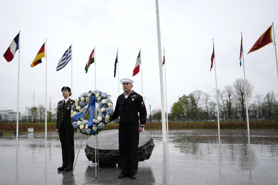 Two military personnel stand underneath the flags of NATO alliance members during wreath laying ceremony at NATO headquarters in Brussels, Thursday, April 4, 2024. NATO celebrates on Thursday 75 years of collective defense across Europe and North America as Russia's war on Ukraine enters its third year. (AP Photo/Virginia Mayo)