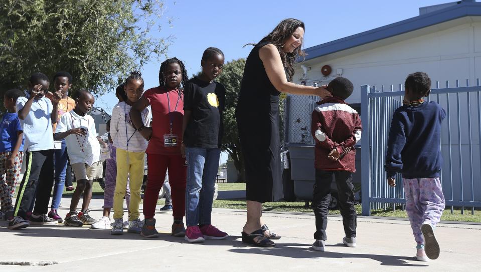 Director Lynette Faulkner, third from right, greets students at Valencia Newcomer School between classes Thursday, Oct. 17, 2019, in Phoenix. Children from around the world are learning the English skills and American classroom customs they need to succeed at so-called newcomer schools. Valencia Newcomer School in Phoenix is among a handful of such public schools in the United States dedicated exclusively to helping some of the thousands of children who arrive in the country annually. (AP Photo/Ross D. Franklin)