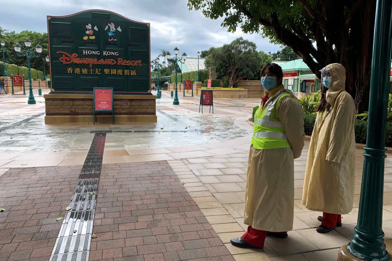 FILE PHOTO: Employees wearing protective masks stand outside the Hong Kong Disneyland theme park that has been closed, following the coronavirus outbreak, in Hong Kong