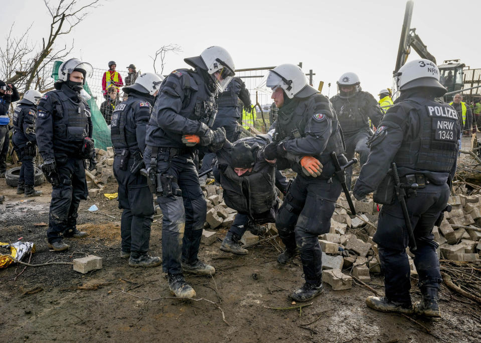 Police officers carry a demonstrator to clear a road at the village Luetzerath near Erkelenz, Germany, Tuesday, Jan. 10, 2023. The village of Luetzerath is occupied by climate activists fighting against the demolishing of the village to expand the Garzweiler lignite coal mine near the Dutch border. (AP Photo/Michael Probst)