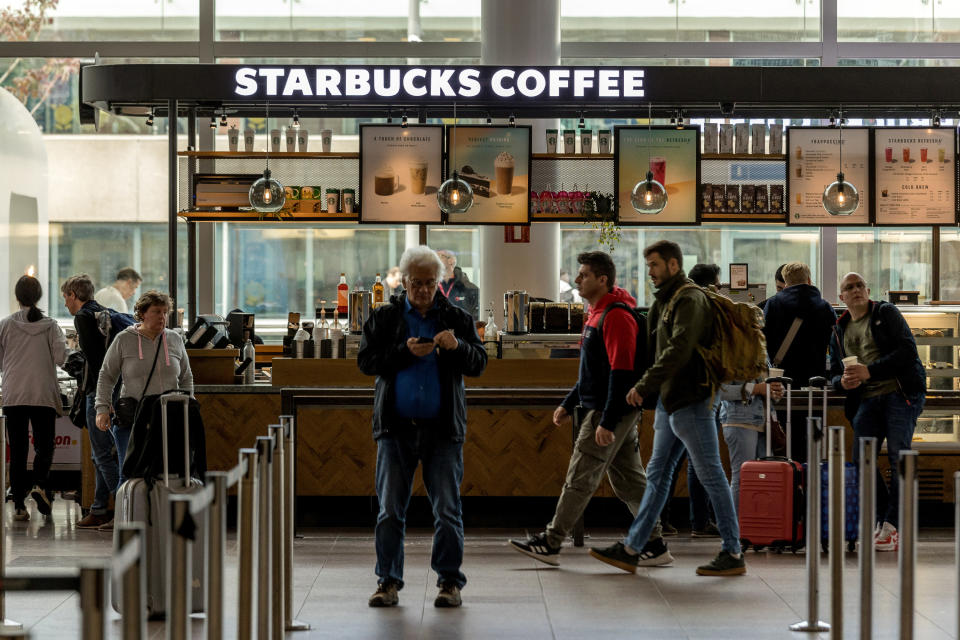 Passengers walk past a Starbucks coffee shop inside the departure terminal of the Belgian capital's airport