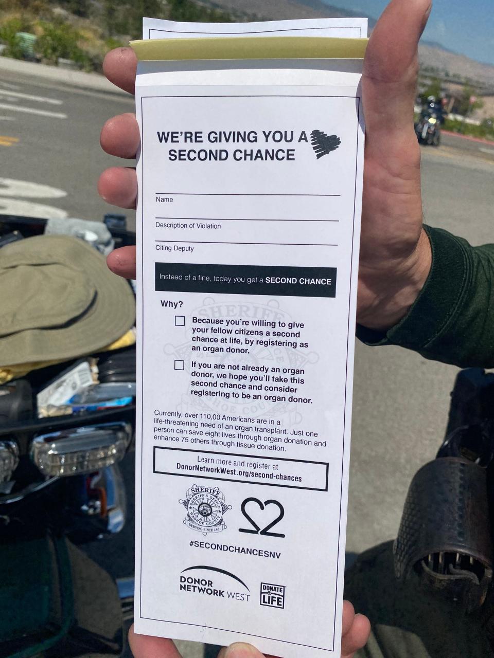 Washoe County Sheriff's Office Deputy Steve Decarli holds a warning ticket with a message about organ donation as part of the 'Second Chance' program this week.