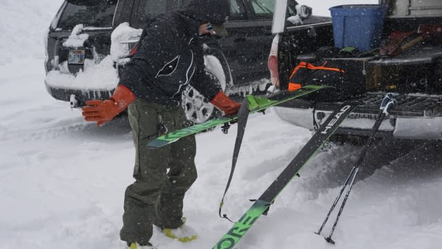 A skier puts skins on his skis before heading into the backcountry.