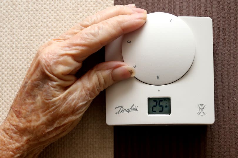 close-up of a hand turning up a thermostat