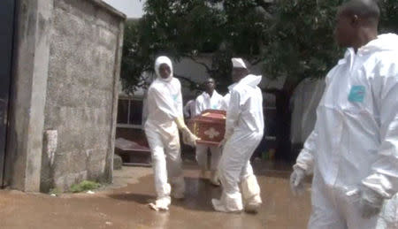 Men wearing protective suits carry a coffin at the Connaught Hospital, Sierra Leone August 15, 2017 in this still image taken from a video. via Reuters TV