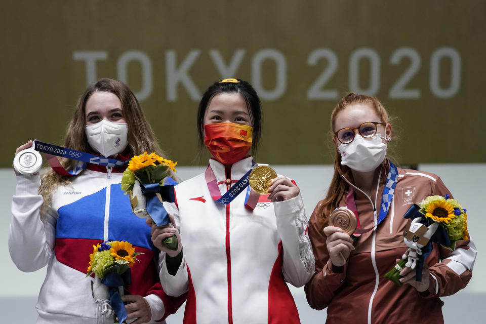 Silver medalist Anastasiia Galashina, left, of the Russian Olympic Committee, gold medalist Yang Qian, of China, center, and bronze medalist Nina Christen, of Switzerland stand after the women's 10-meter air rifle at the Asaka Shooting Range in the 2020 Summer Olympics, Saturday, July 24, 2021, in Tokyo, Japan.(AP Photo/Alex Brandon)