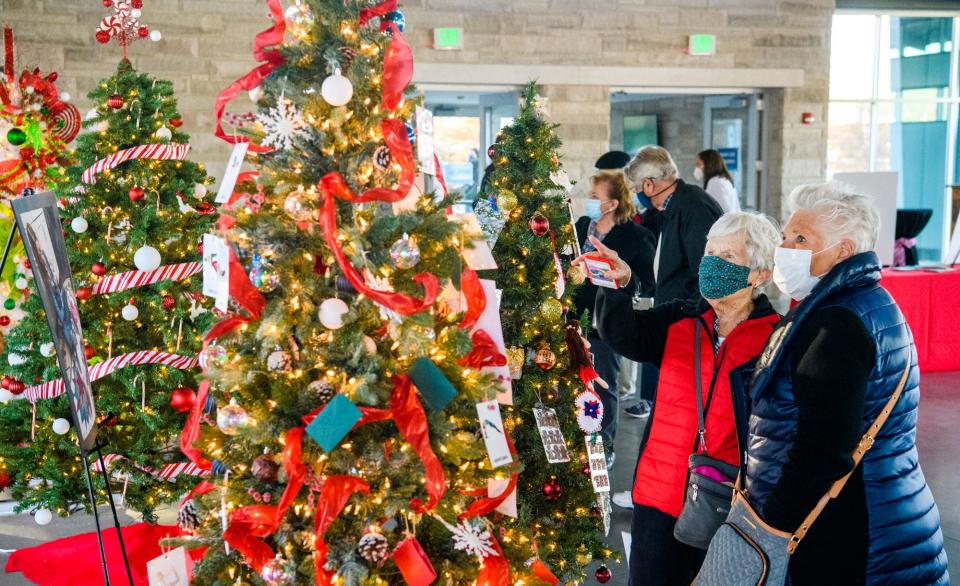 Ciindy DeAtley, center in red, and Marcia Miller, right, look at the decorated trees at Hope for the Holidays Tree Extravaganza & Auction benefitting New Hope For Families at the Switchyard Park Pavilion on Nov. 18.