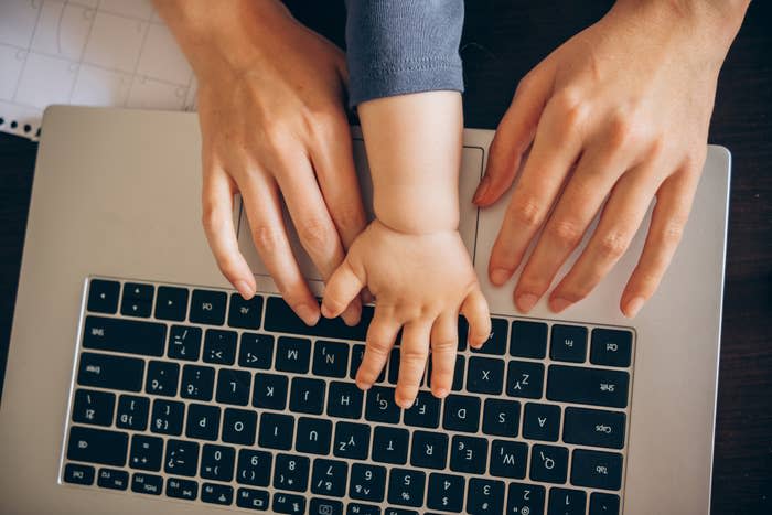 Adult hands and baby hands on a laptop keyboard, symbolizing shared parenting and digital interaction