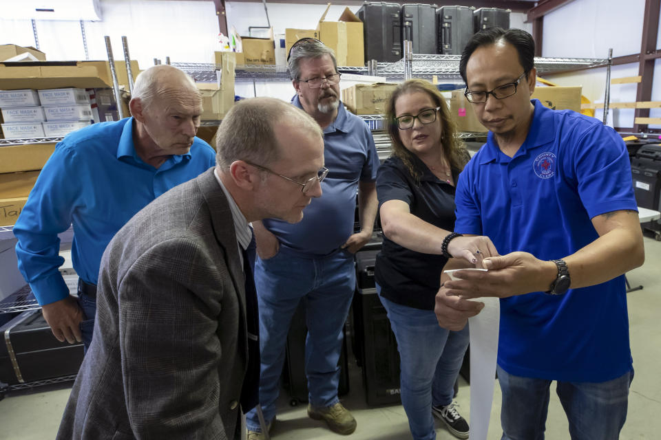 Torrance County deputy clerk Silvia Chavez, second from right, and administrative assistant clerk Kevin Pham, right, explain the tabulation receipt to local candidates and partisan officers during a ballot-counting machines testing in Estancia, N.M., Sept. 29, 2022. (AP Photo/Andres Leighton)