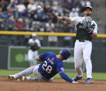 Colorado Rockies shortstop Ezequiel Tovar, right, throws to first base after forcing out Texas Rangers' Jonah Heim (28) at second base in the second inning of a baseball game Saturday, May 11, 2024, in Denver. (AP Photo/Jerilee Bennett)