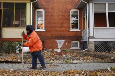 Ardana McFerren sweeps leafs outside of her home in the historic Pullman neighborhood in Chicago November 20, 2014. REUTERS/Andrew Nelles