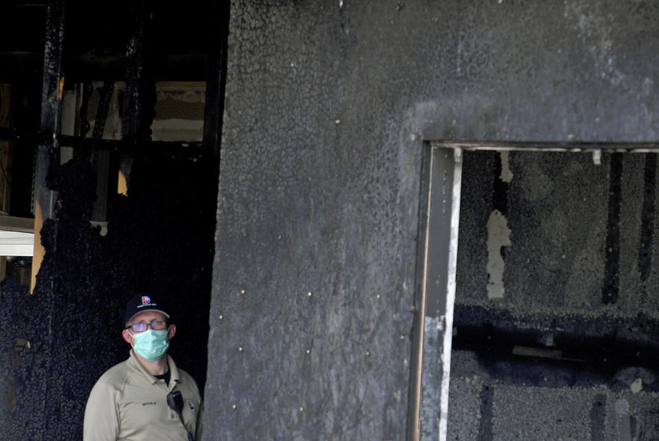 An investigator stands in the doorway of a home in suburban Denver on Wednesday, Aug. 5, 2020, where five people were found dead after a fire. Three people escaped the fire by jumping from the home's second floor. Investigators believe the victims were a toddler, an older child and three adults. Authorities suspect was intentionally set. Witnesses told firefighters that three people on the second floor of the burning home jumped to safety. A fire department spokesman said the fire's heat pushed back a police officer trying to rescue the people who were on the home's first floor. (AP Photo/Thomas Peipert)