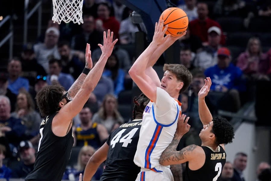 Florida forward Alex Condon, center, grabs a rebound between Colorado guard J’Vonne Hadley, left, and guard KJ Simpson, right, in the second half of a first-round college basketball game in the NCAA Tournament, Friday, March 22, 2024, in Indianapolis, Ind. (AP Photo/Michael Conroy)