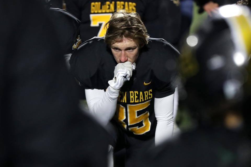 Upper Arlington's Austin Stutz listens as head coach Justin Buttermore addresses the team following a 16-10 loss to Lakewood St. Edward in a Division I OHSAA State Semifinal game Nov. 26, 2021, at Mansfield Senior High School's Arlin Field in Mansfield, Ohio.