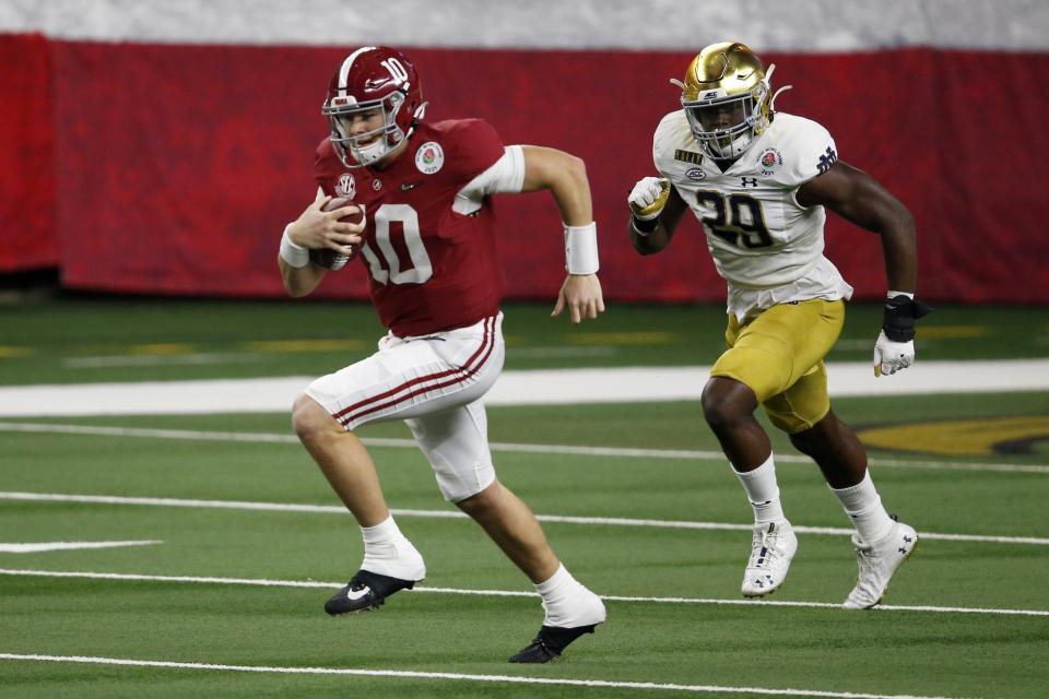 Alabama quarterback Mac Jones, pictured running past Notre Dame defensive lineman Ovie Oghoufo in a CFP semifinal on Jan. 1, isn't known for his rushing skills. (AP Photo/Roger Steinman)