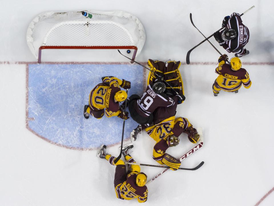 Union's Eli Lichtenwald, upper right, watches his shot get past Minnesota's Adam Wilcox, center, for a goal during the first period of an NCAA men's college hockey Frozen Four tournament game on Saturday, April 12, 2014, in Philadelphia. (AP Photo/Chris Szagola)