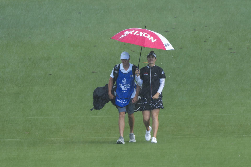 Australia's Hannah Green walks with her caddy in heavy rain on the sixth fairway during the first round of the Australian Open Golf Championship in Sydney, Australia, Thursday, Nov. 30, 2023. (AP Photo/Mark Baker)