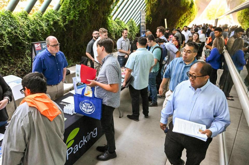 Job-seekers browse tables representing dozens of prospective employers during a job fair hosted by Workforce Connection and the City of Fresno in response to the laying off of 300 Fresno employees from Bitwise Industries, at Fresno City Hall on Friday, June 16. 2023. CRAIG KOHLRUSS/ckohlruss@fresnobee.com
