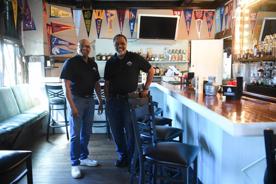 Magnolia Cafe co-owners Frank Shanklin, left, and Rep. Sam McKenzie celebrate historically Black colleges and universities by hanging school pennants brought by alumni who eat there.