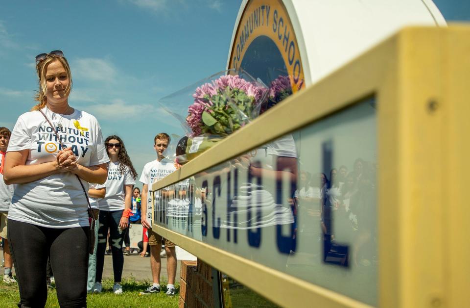 Jill Soave, left, the mother of slain Oxford High School student Justin Shilling, takes a moment of reflection after she placed flowers at a sign at the entrance to the school after a moment of silence as they arrive at Oxford High School during the March For Our Lives Oxford event on Saturday, June 11, 2022. Students, teachers and parents shared their stories of loss following the shooting at the school and demanded that lawmakers enact gun control laws to keep these tragedies from happening again. When the crowd reached the high school, it held a moment of silence to honor and remember the teens who were gunned down, Madisyn Baldwin, Tate Myre, Justin Shilling, and Hana St. Juliana.