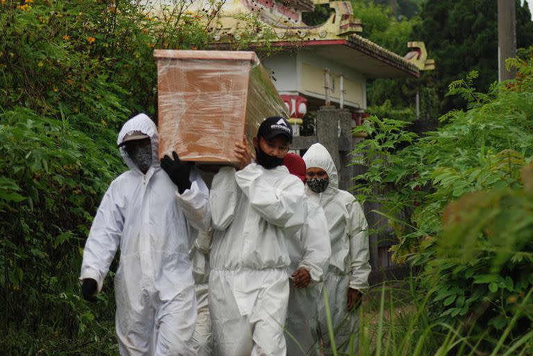 Personal del cementerio lleva un ataúd para el entierro en un lugar designado para las víctimas de Covid-19 en Bandung