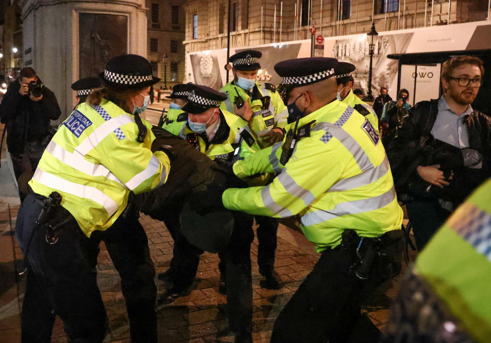 Police officers detain a man on Monday night during protests following the kidnap and murder of Sarah Everard.