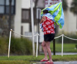 A woman uses a beach umbrella to stay dry as she crosses Scenic Highway 98 in Miramar Beach, Fla., Tuesday Sept. 4, 2018, as Tropical Storm Gordon makes its way past the Florida Panhandle. (Devon Ravine/Northwest Florida Daily News via AP)