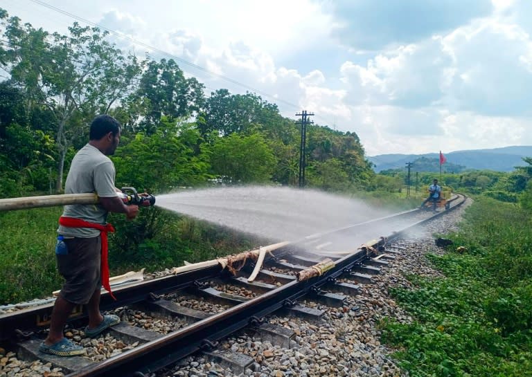 Un operario ferroviario moja las vías de tren que se estaban derritiendo por el elevado calor en Tailandia, en la provincia sureña de Nakhon Si Thammarat (Handout)