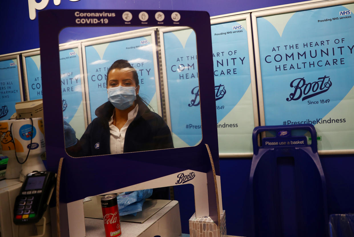 A Boots employee wearing a face mask works at a counter behind a protective screen at a store in London, as the spread of the coronavirus disease (COVID-19) continues, London, Britain, April 8, 2020. REUTERS/Hannah McKay