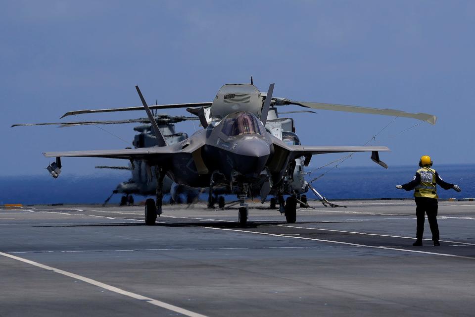 A crew member makes a signal to F-35 aircraft for take off on the UK's aircraft carrier HMS Queen Elizabeth in the Mediterranean Sea on June 20, 2021.
