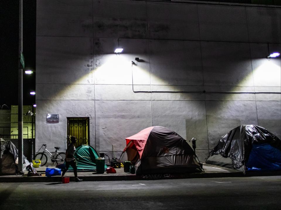 <p>A homeless man is seen among tents on the street of Skid Row during the Covid-19, Coronavirus pandemic in Los Angeles, California on 16 May 2020</p> ((AFP via Getty Images))