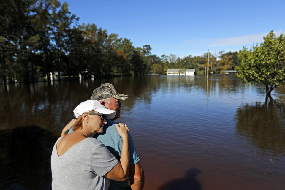 FILE - In this Tuesday, Sept. 18, 2018 file photo, Dianna Wood embraces her husband, Lynn, as they look out over their flooded property as the Little River continues to rise in the aftermath of Hurricane Florence in Linden, N.C. According to a study released on Wednesday, Nov. 11, 2020, hurricanes are keeping their staying power longer once they make landfall, spreading more inland destruction. (AP Photo/David Goldman)