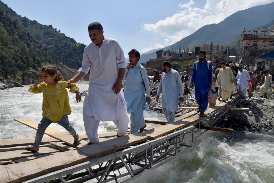 People walking across a makeshift bridge