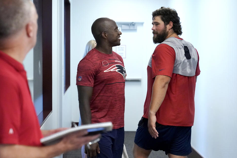 New England Patriots wide receiver Matthew Slater, center, and Patriots center David Andrews, right, pass one another in a hallway as Slater arrives to take questions from the media at a news conference, Tuesday, July 25, 2023, in Foxborough, Mass. (AP Photo/Steven Senne)