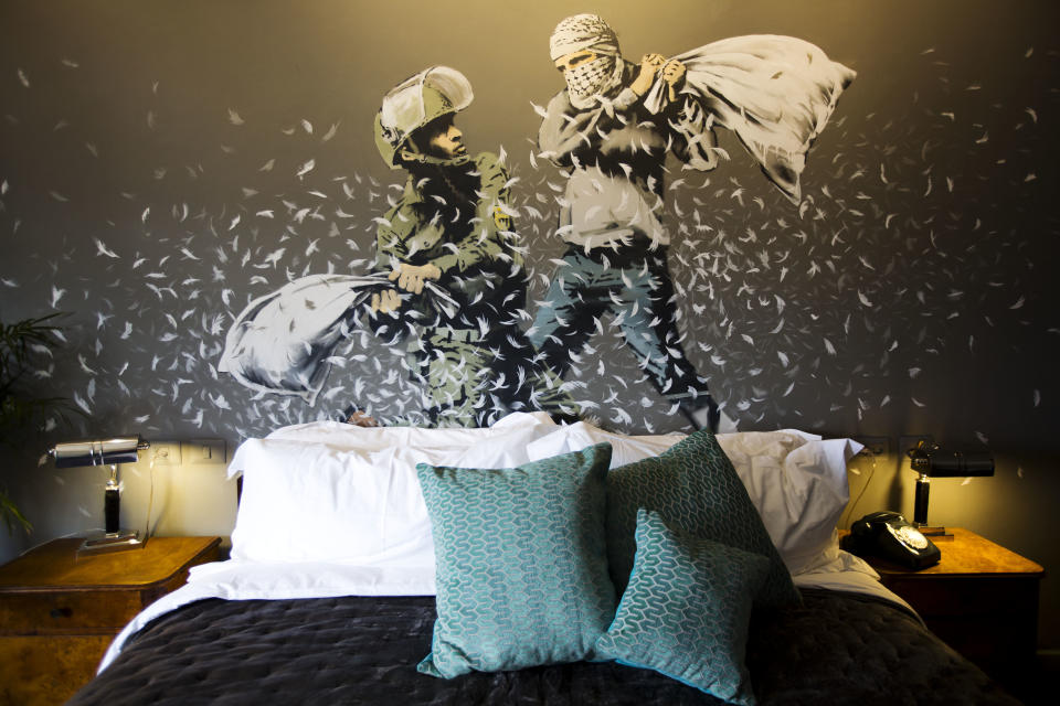 Una obra de Bansky que muestra a un palestino y un soldado israelí fajándose a almohadonazos decora una de las habitaciones de The Walled Off Hotel en Belén. Foto del 3 de marzo del 2019. (AP Photo/Dusan Vranic, File)